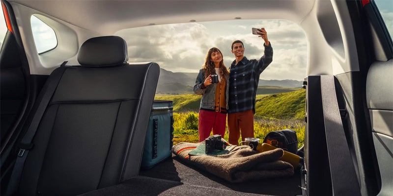 Hyundai Kona cargo area with passengers enjoying an outdoor adventure near a scenic landscape.