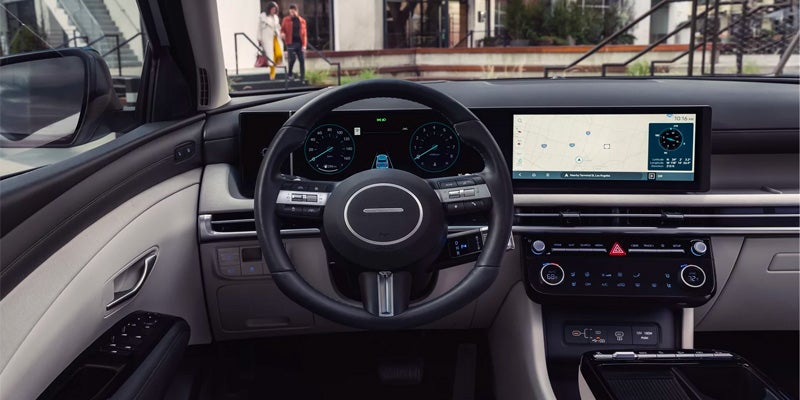 Hyundai Tucson interior with digital dashboard, steering wheel, and navigation display.