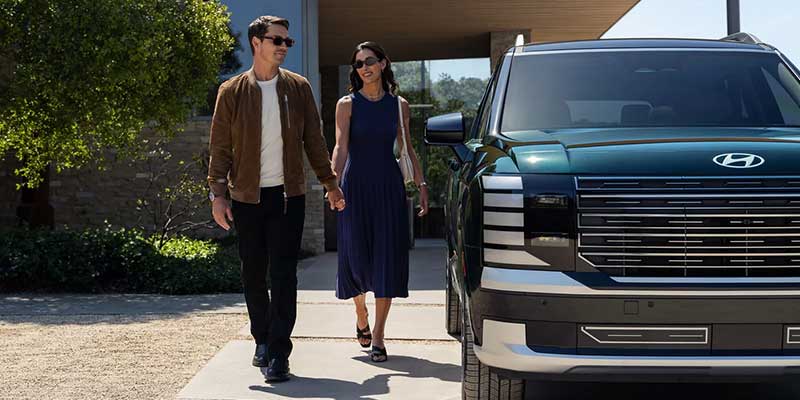 Hyundai Palisade with passengers walking near a modern home showcasing lifestyle appeal.