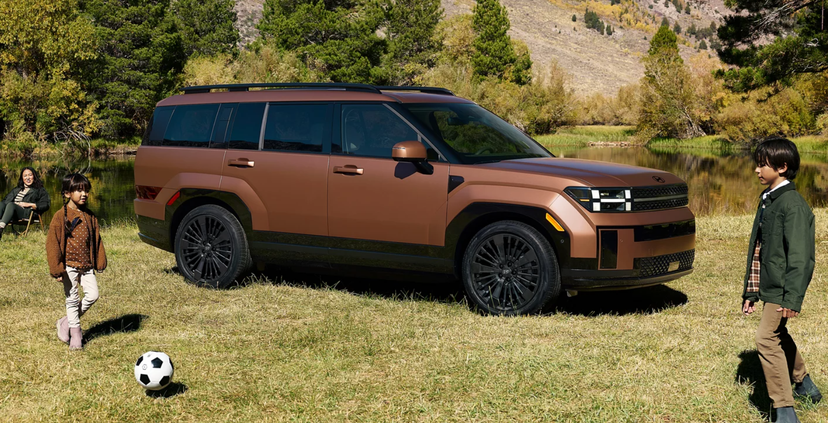 2026 Hyundai Santa Fe parked in soccer feild with 2 kids playing.