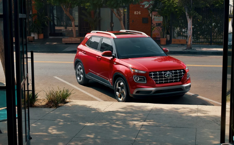 Red 2026 Hyundai Venue parked outside of shops.