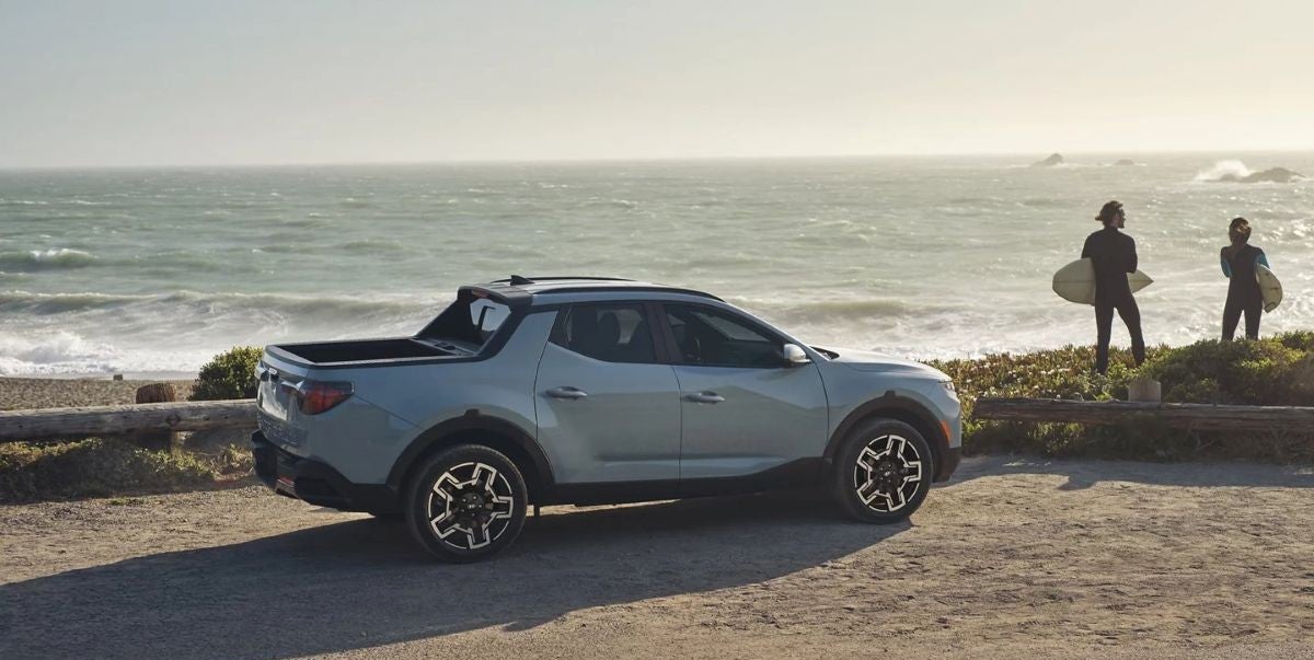 Hyundai Santa Cruz parked by the beach with surfers preparing to enter the ocean near Windward Hyundai.